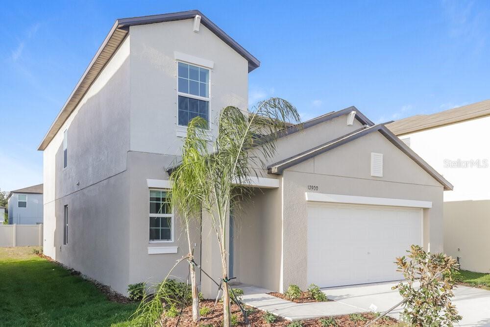 A two-story suburban house with a beige stucco exterior and an attached two-car garage — 17900 BEAMING RAYS LANE, LUTZ, FL