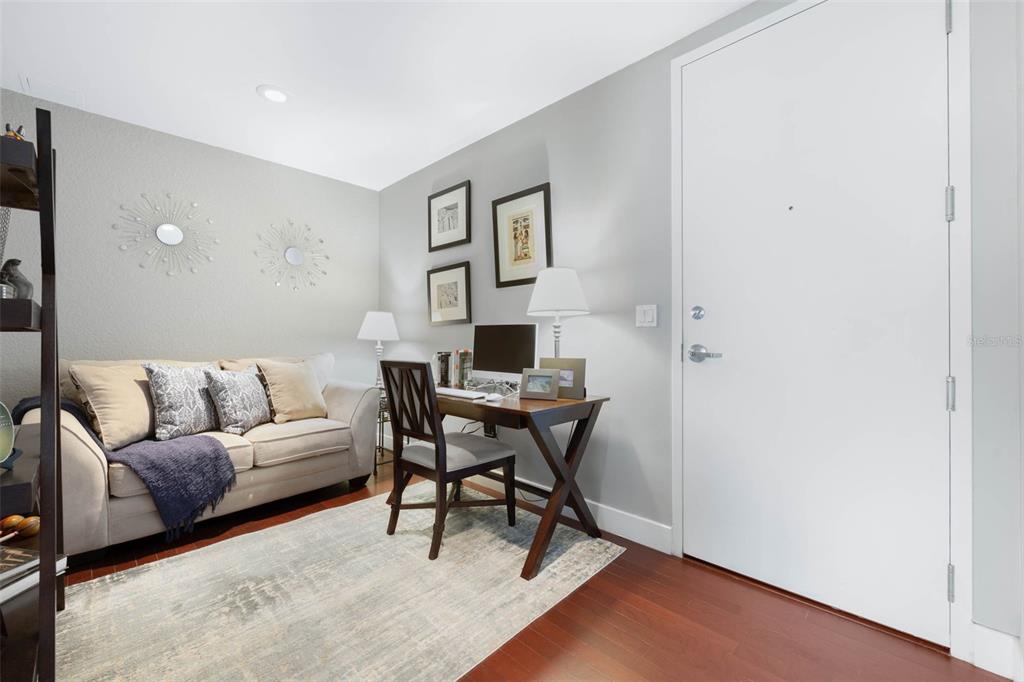 A home office with a sofa, desk, chair, and a white door on hardwood floors — 150 E ROBINSON STREET UNIT 3104-1, ORLANDO, FL