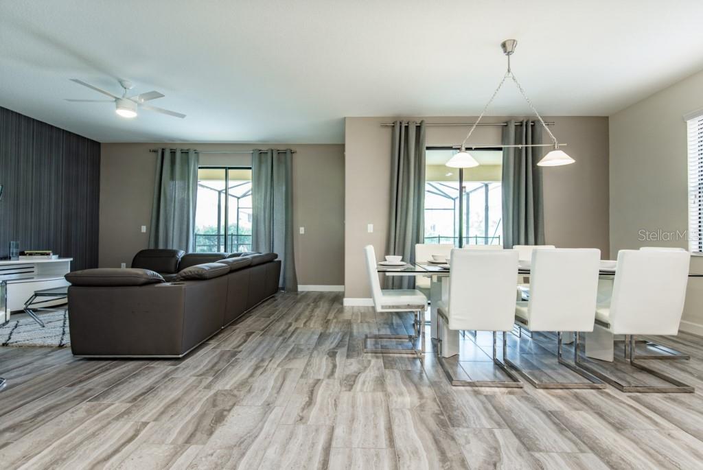 An open-concept living and dining area features wood-look tile flooring and a modern chandelier — 5425 SOLTERRA CIRCLE, DAVENPORT, FL