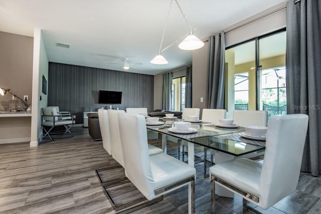 A dining room with a glass table and white chairs sits adjacent to a living area — 5425 SOLTERRA CIRCLE, DAVENPORT, FL
