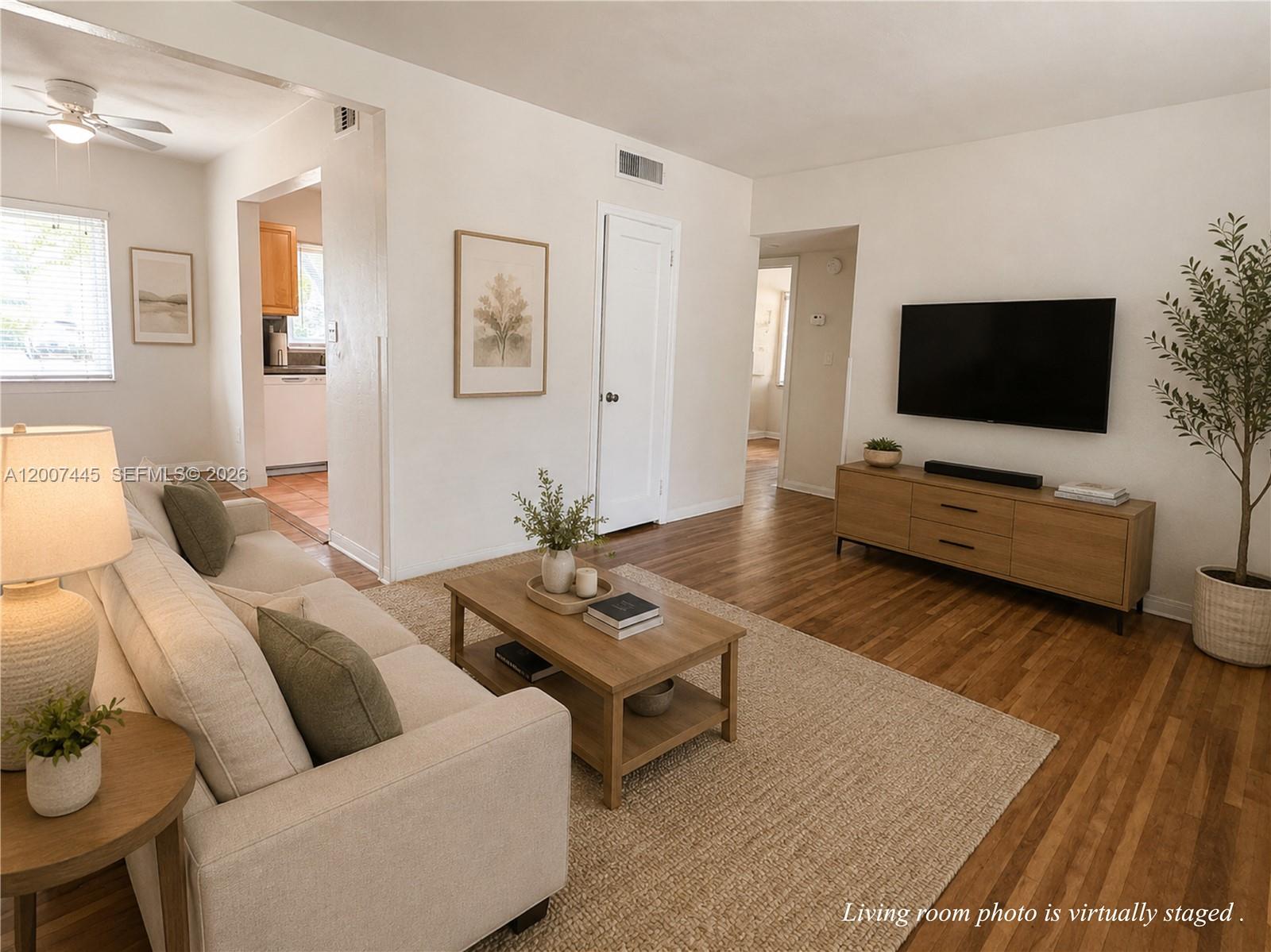 A living room with wood floors, a beige sofa, and a wall-mounted television — 7734 SW 55th Ave # B, Miami FL 33143, MIAMI, FL