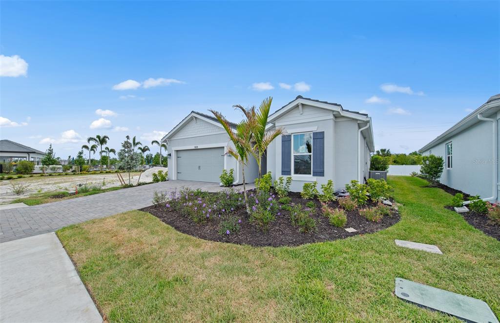 A single-story house with a gray garage, light-colored siding, and a small front garden — 1828 SILVER SHORES BOULEVARD, ENGLEWOOD, FL