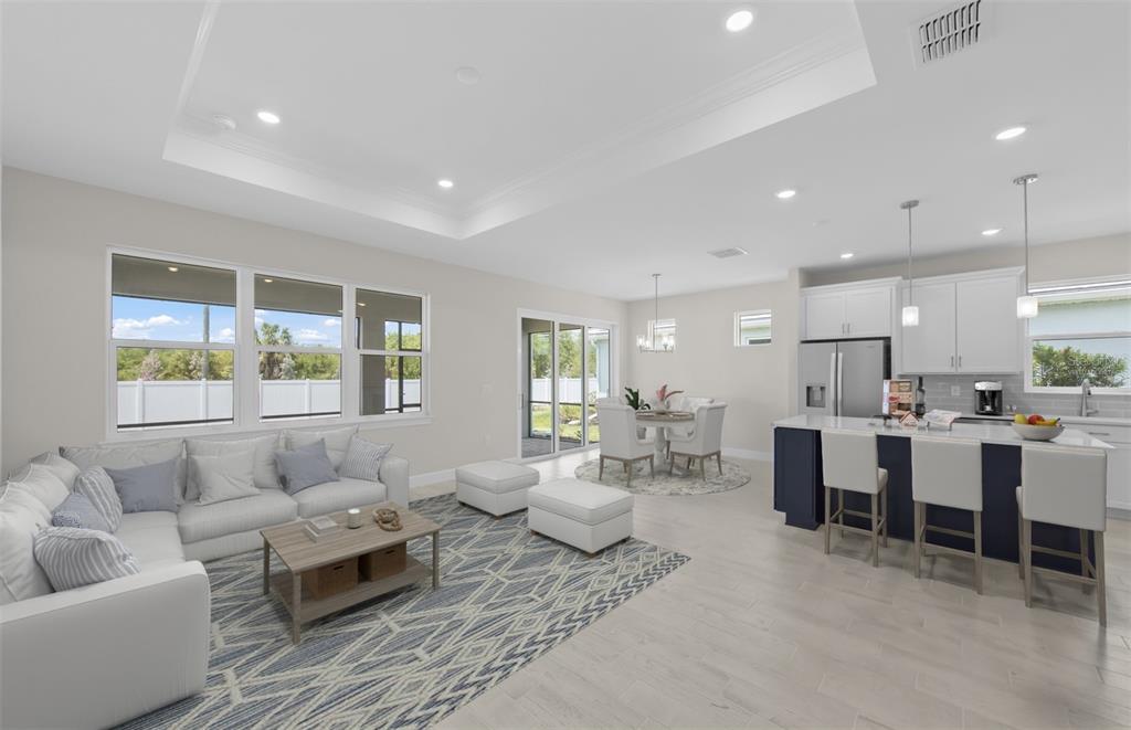 An open-concept living room and kitchen feature white cabinetry, a blue island, and tile flooring — 1828 SILVER SHORES BOULEVARD, ENGLEWOOD, FL