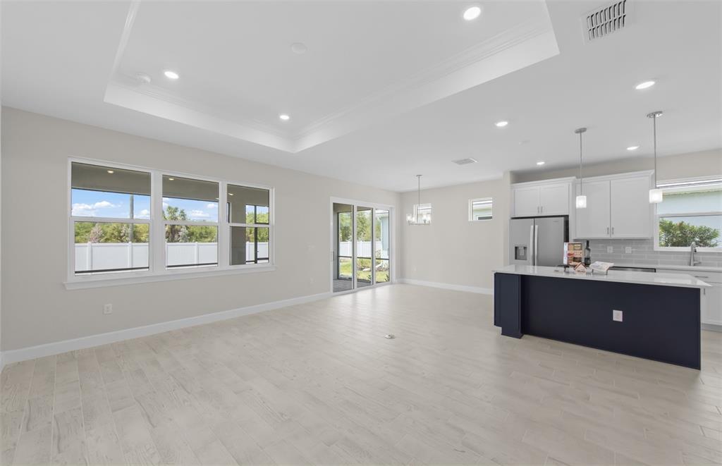 An open-concept living area features a kitchen with a dark blue island and light flooring — 1828 SILVER SHORES BOULEVARD, ENGLEWOOD, FL