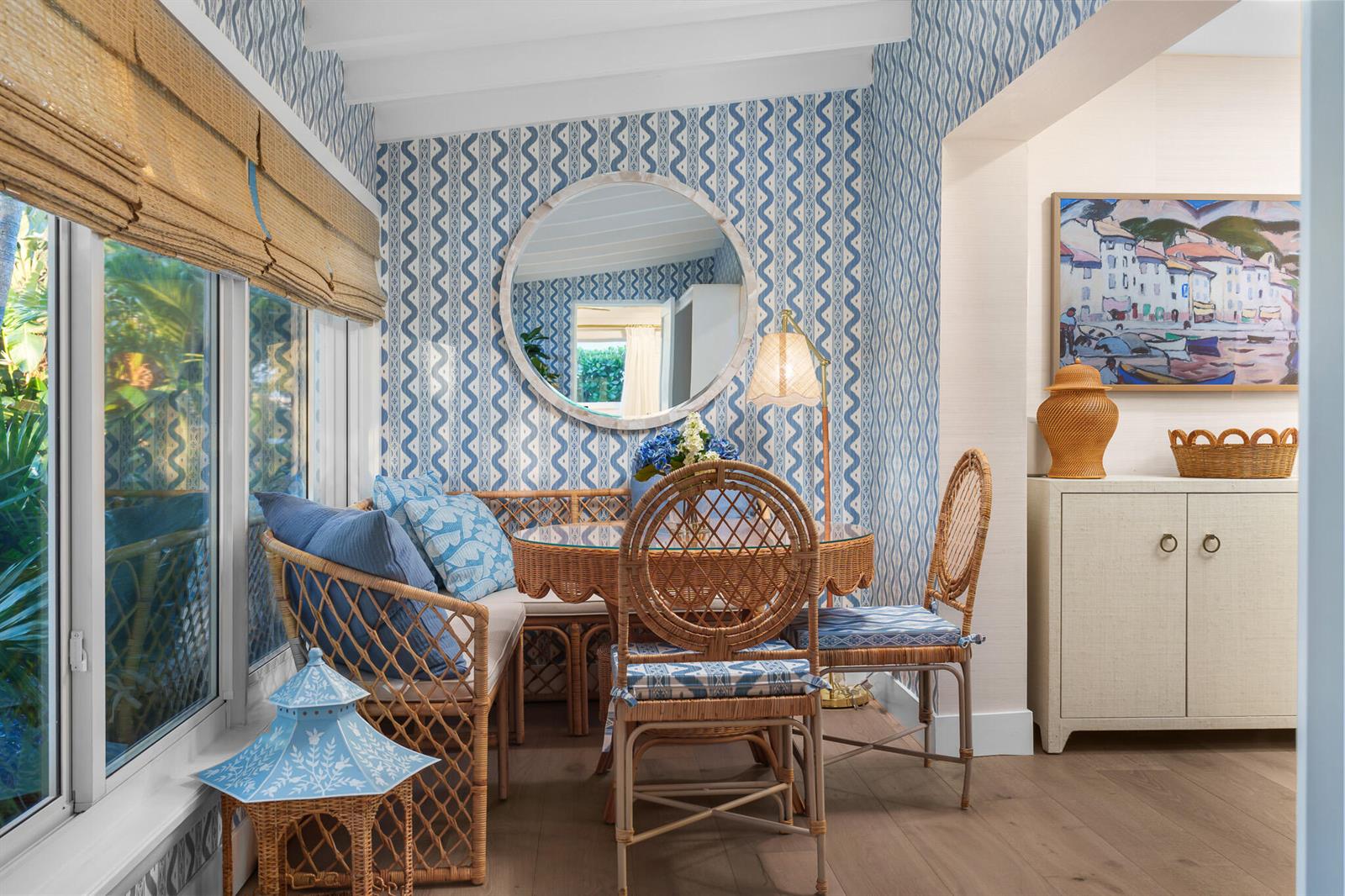 A breakfast nook features blue patterned wallpaper, a round mirror, and wicker dining furniture — 7 Fayette Drive, Ocean Ridge FL 33435, OCEAN RIDGE, FL