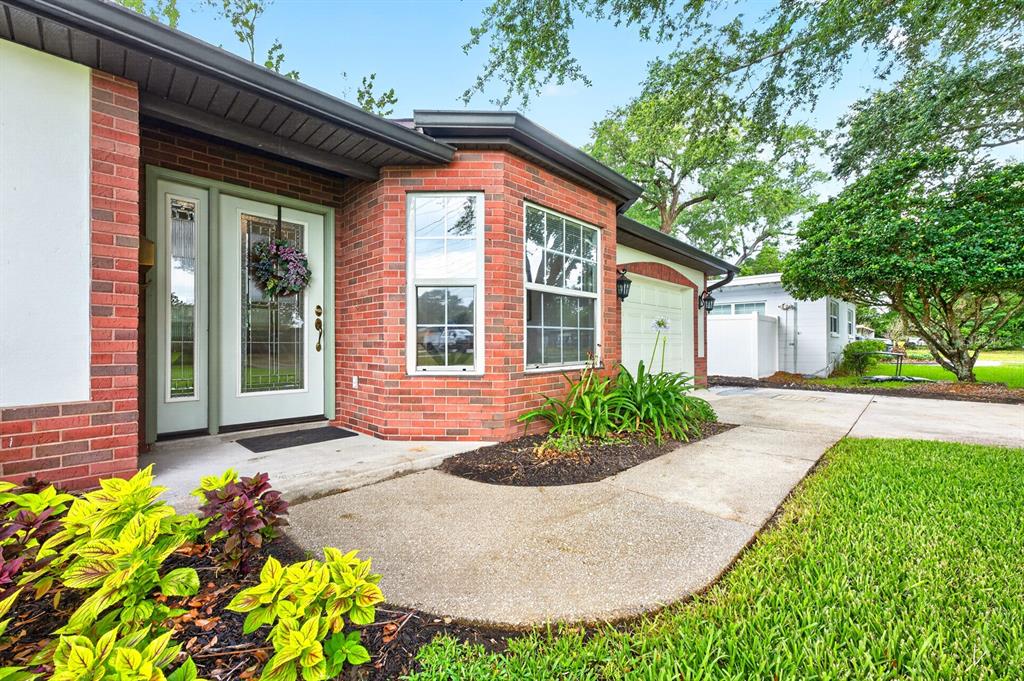 A brick house exterior features a front entrance with a white door and bay windows — 2706 HARGILL DRIVE, ORLANDO, FL