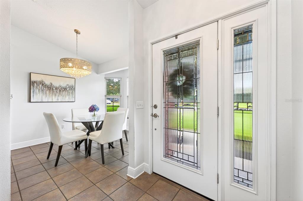A dining area with a glass table and chandelier sits beside a white front door — 2706 HARGILL DRIVE, ORLANDO, FL