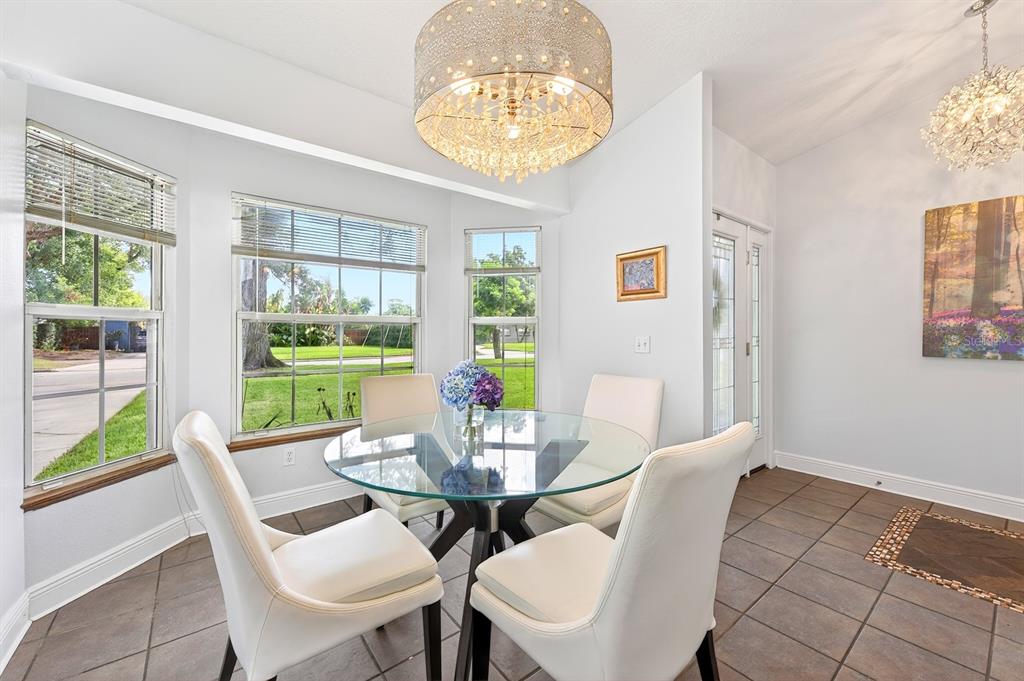 A dining area features a glass table, four white chairs, tile flooring, and two chandeliers — 2706 HARGILL DRIVE, ORLANDO, FL