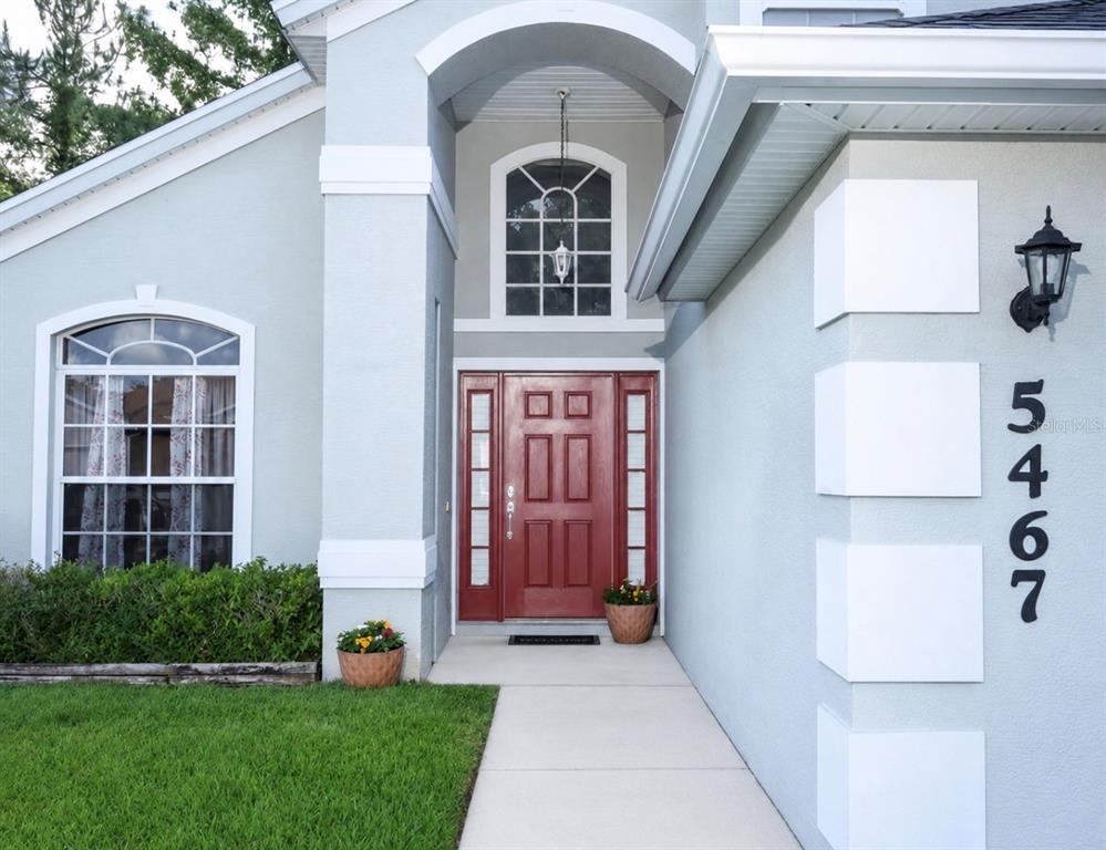 The exterior of a light blue house features a red front door and house numbers — 5467 WARD LAKE DRIVE, PORT ORANGE, FL