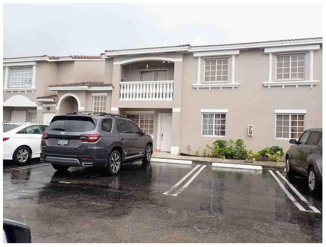 A two-story townhouse exterior with a balcony, stucco siding, and a parking lot — 7281 NW 174th Ter # 103, Hialeah FL 33015, HIALEAH, FL