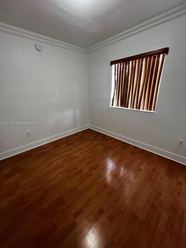 An empty room features white walls, wood-look flooring, and a window with brown vertical blinds — 7281 NW 174th Ter # 103, Hialeah FL 33015, HIALEAH, FL