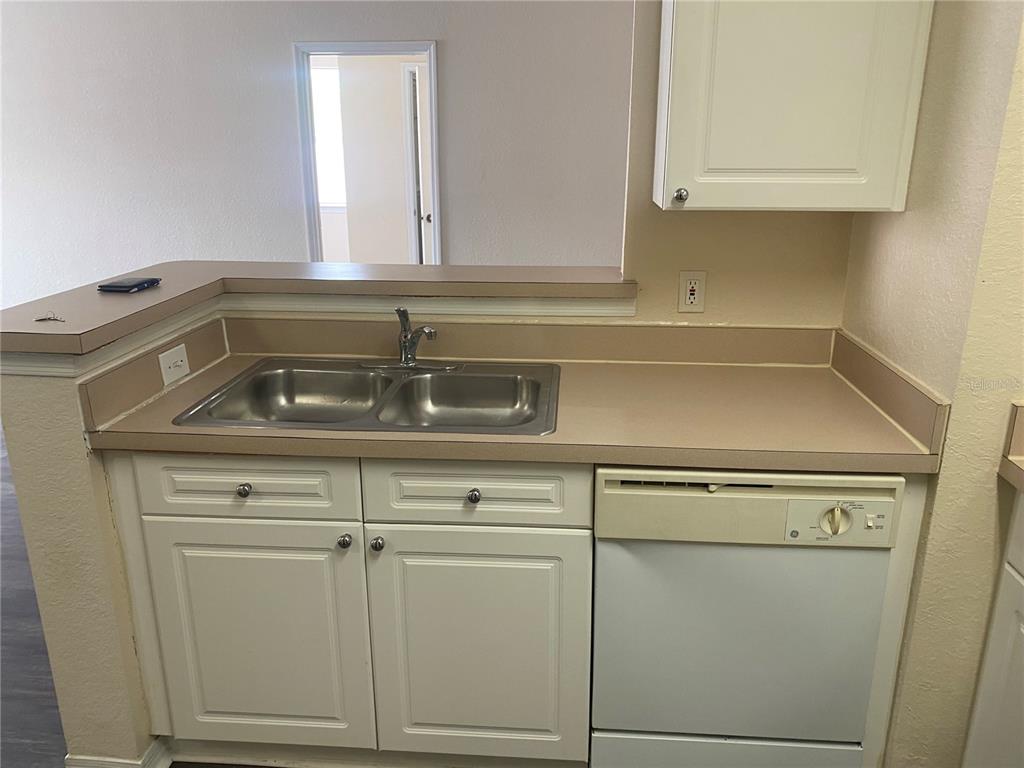 A kitchen sink area features white cabinets, a beige countertop, and a white dishwasher — 18001 RICHMOND PLACE DRIVE UNIT 222, TAMPA, FL