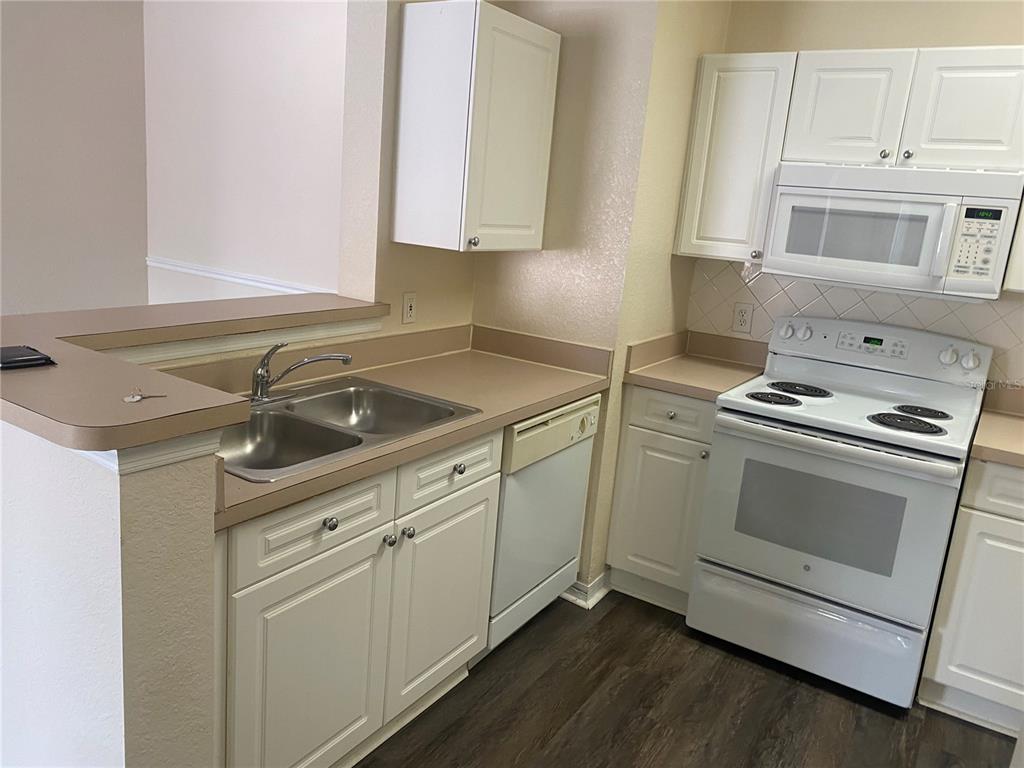 A kitchen features white cabinets, laminate countertops, a double sink, and white appliances — 18001 RICHMOND PLACE DRIVE UNIT 222, TAMPA, FL