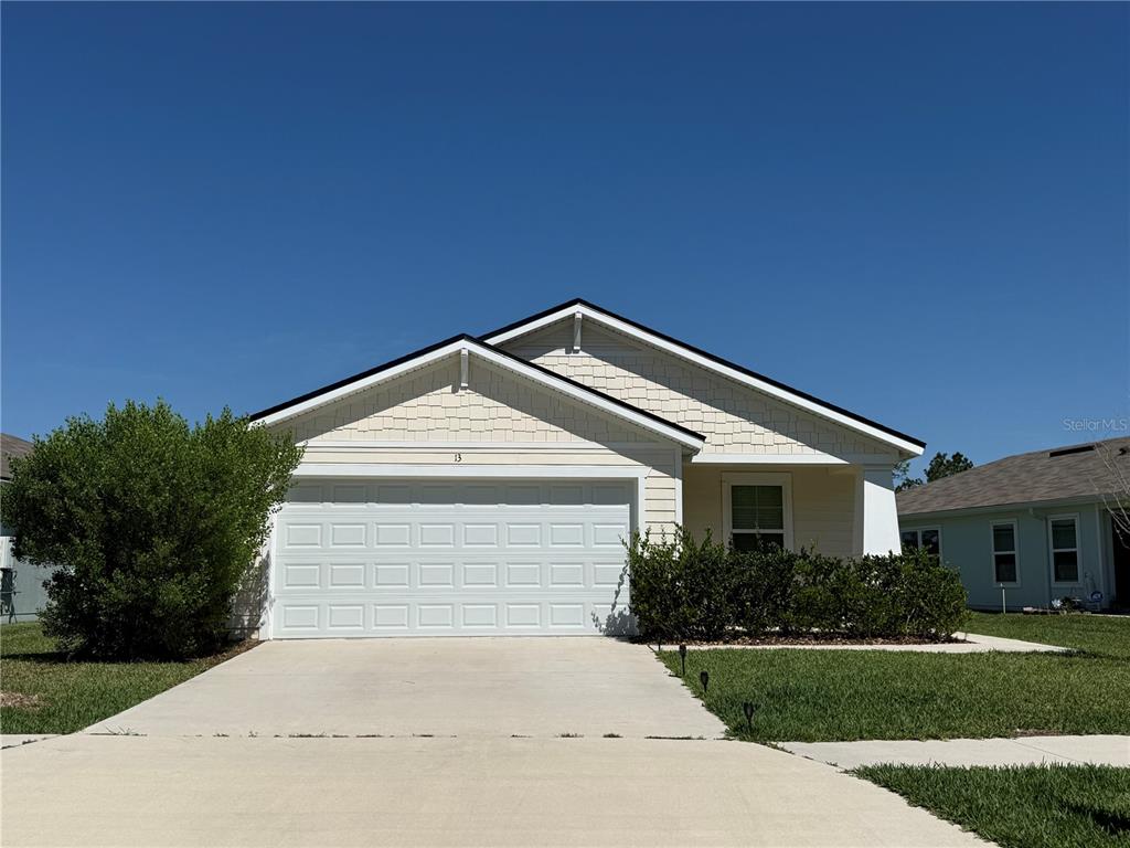 A single-story house with a white garage door, light siding, and a concrete driveway — 13 PINNACLE PLACE, BUNNELL, FL