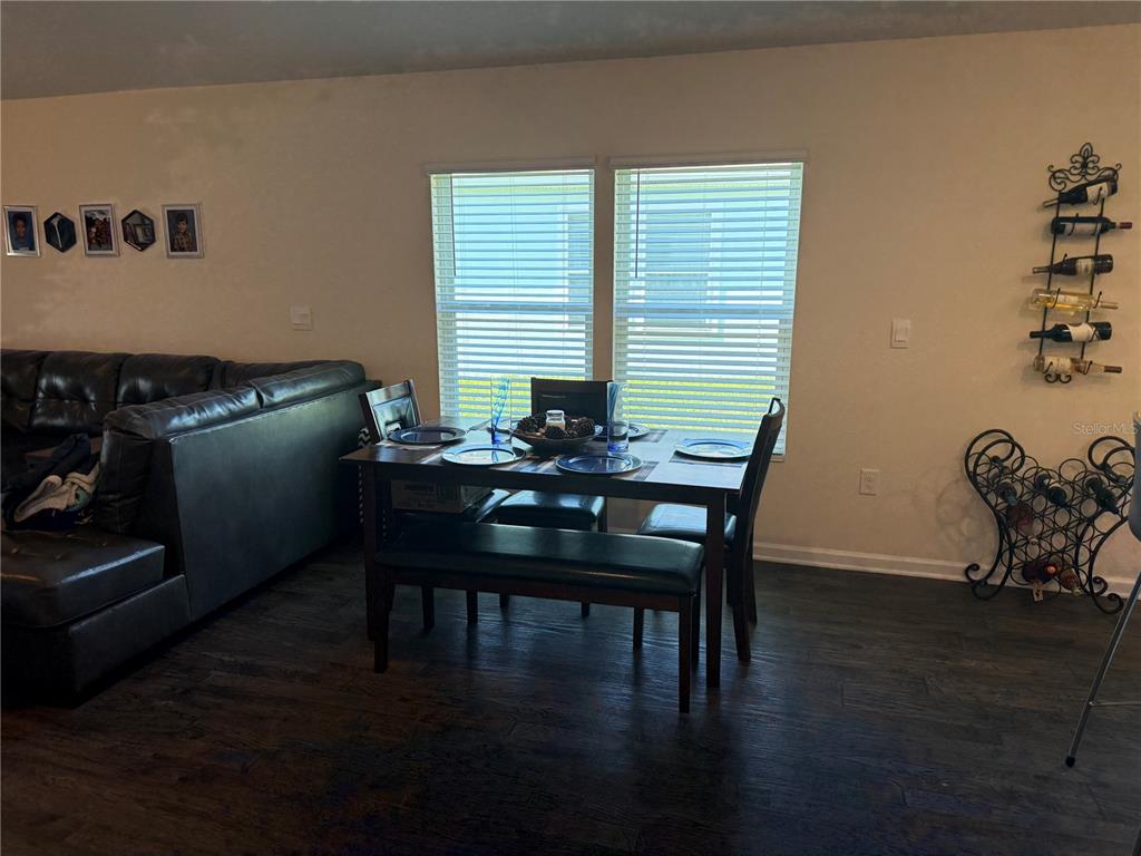 A dining area with a dark wood table, bench, and chairs sits before two windows — 13 PINNACLE PLACE, BUNNELL, FL
