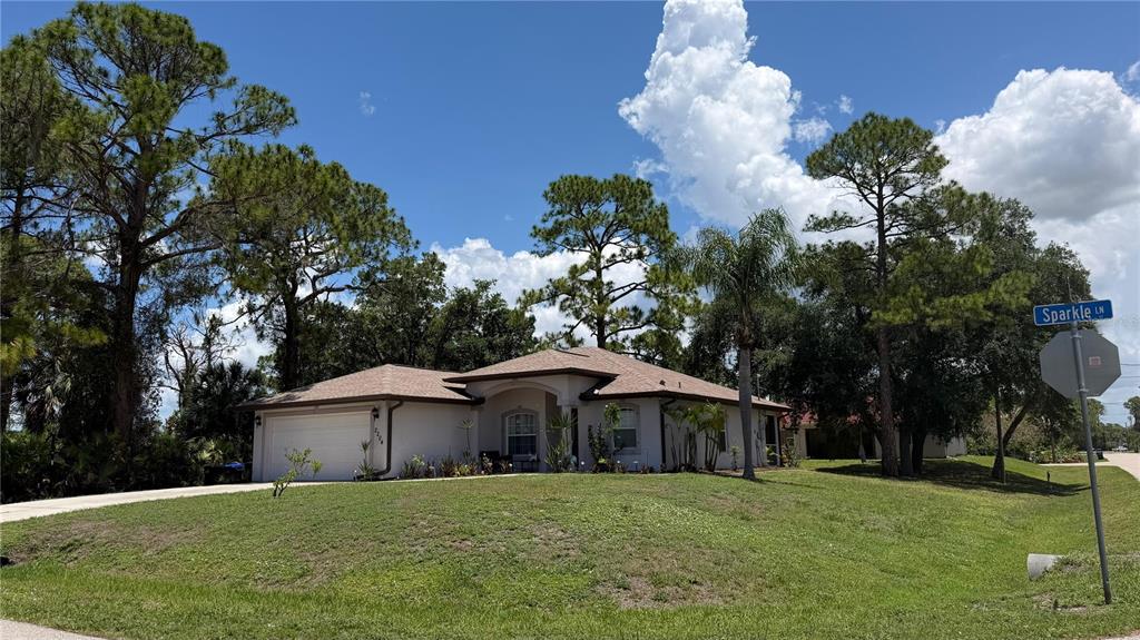 A single-story house with a tan exterior and a two-car garage sits on a lawn — 2204 SPARKLE LANE, NORTH PORT, FL
