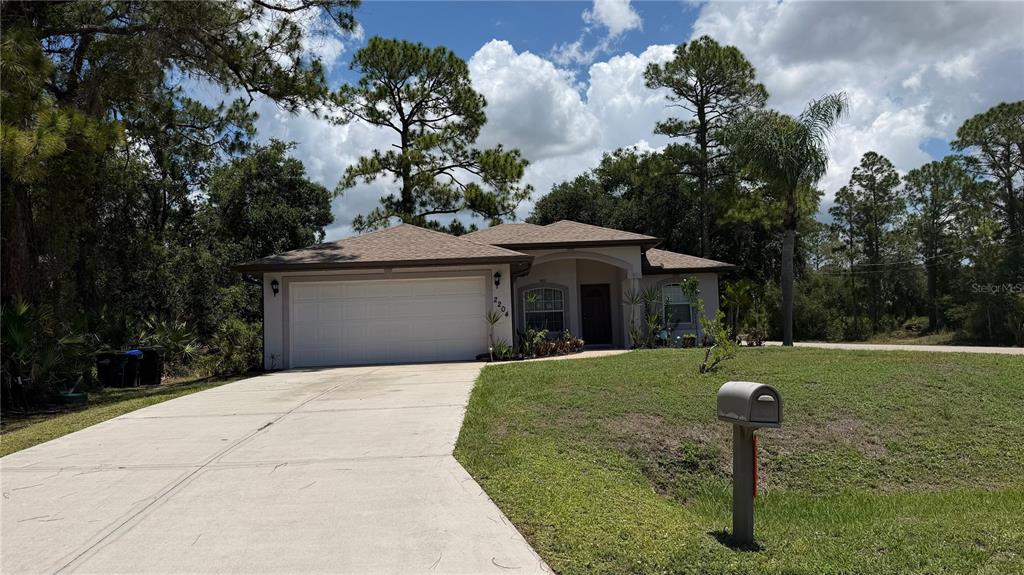 A single-story house with a white garage door, beige exterior, and a concrete driveway — 2204 SPARKLE LANE, NORTH PORT, FL