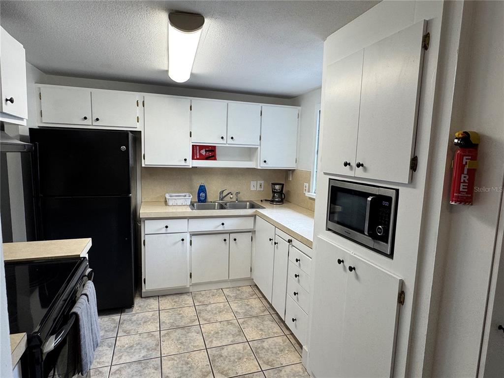A kitchen features white cabinetry, black appliances, a double sink, and tiled flooring — 2111 S CRYSTAL LAKE DRIVE, LAKELAND, FL