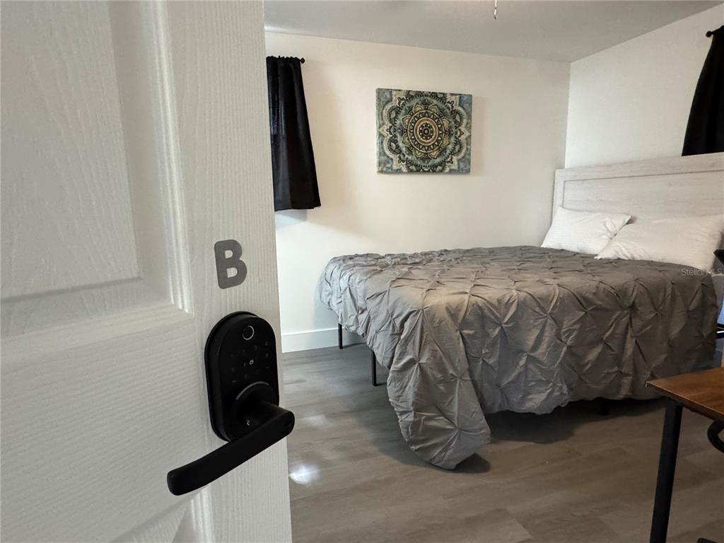 A bedroom features a bed with a gray comforter, a mandala wall art piece, and a door — 2111 S CRYSTAL LAKE DRIVE, LAKELAND, FL