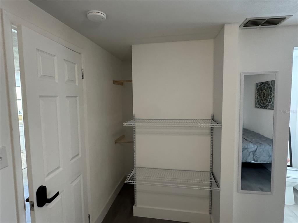 A walk-in closet features white wire shelving, a white door, and a wall-mounted mirror — 2111 S CRYSTAL LAKE DRIVE, LAKELAND, FL