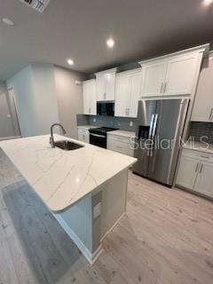 A modern kitchen features white cabinets, a large quartz-topped island, and stainless steel appliances — 3490 TIMBER CROSSING AVENUE, BRANDON, FL