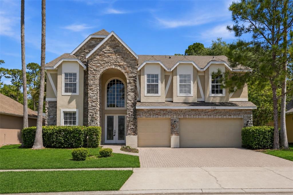 A two-story suburban house features a stone facade, arched entryway, and a three-car garage — 11027 SUMMERSPRING LAKES DRIVE, ORLANDO, FL