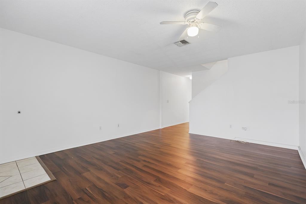An empty living room features white walls, dark wood-look flooring, and a ceiling fan — 1326 TWILRIDGE PLACE, BRANDON, FL