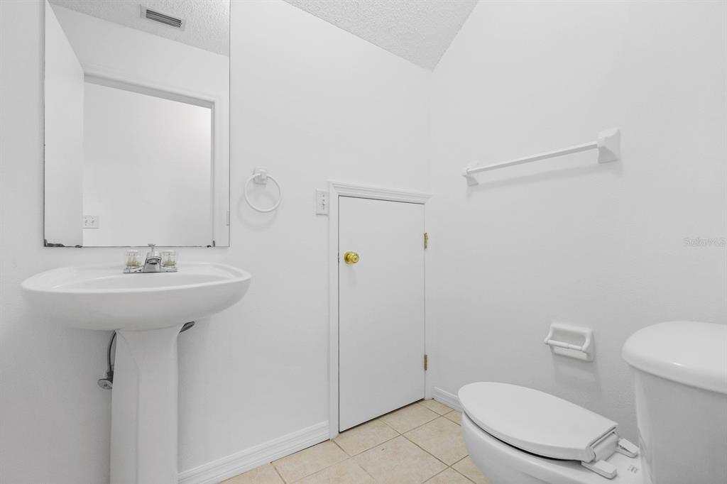 A small bathroom features a pedestal sink, a toilet, and a low storage access door — 1326 TWILRIDGE PLACE, BRANDON, FL