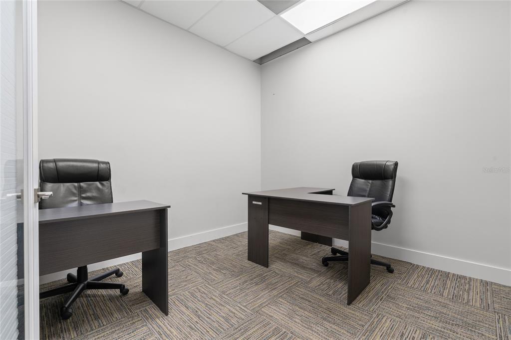 A small office room features two dark wood desks, black chairs, and patterned carpet flooring — 40 SW 1ST STREET, OCALA, FL