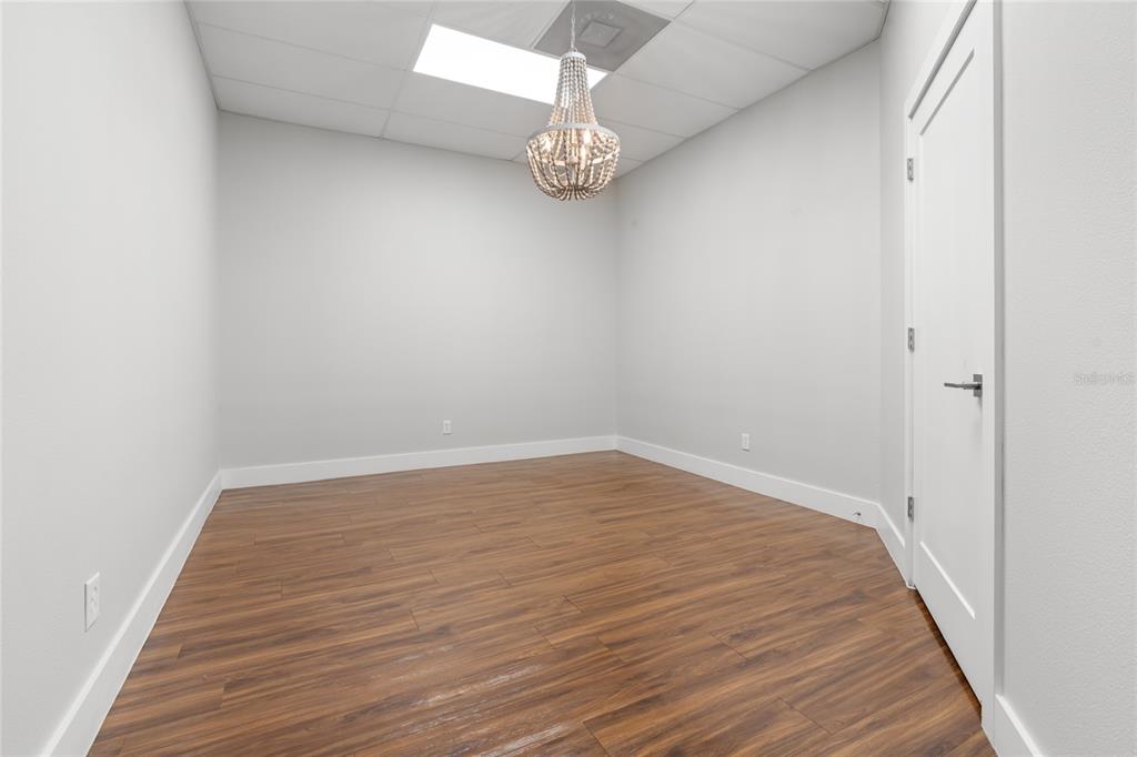 An empty room with wood-look flooring, light gray walls, and a beaded chandelier — 40 SW 1ST STREET, OCALA, FL