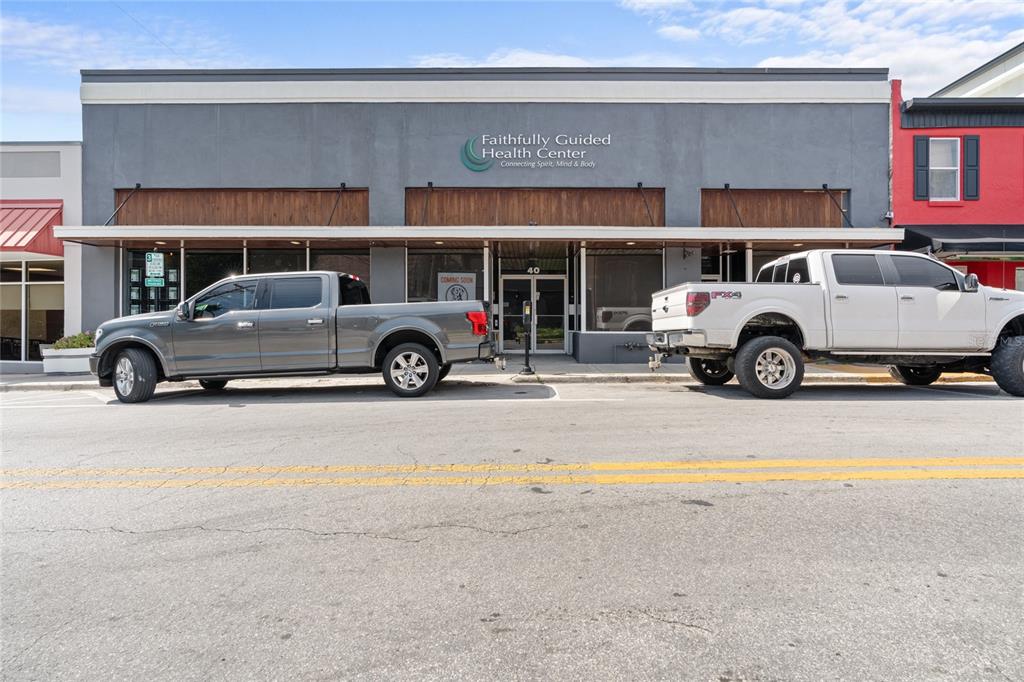 A gray commercial building with a health center sign sits behind two parked pickup trucks — 40 SW 1ST STREET, OCALA, FL