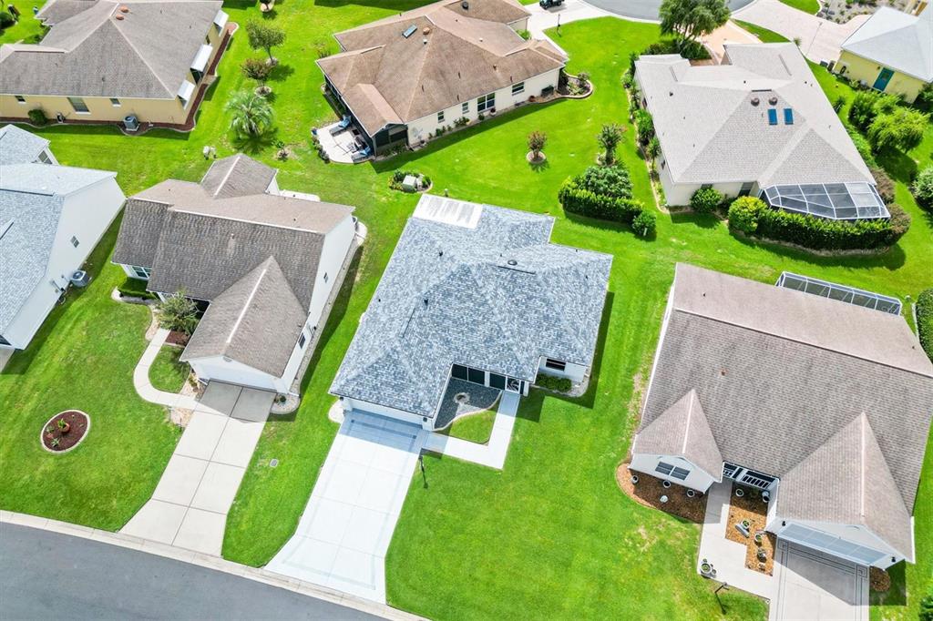 An aerial view shows several suburban houses with shingled roofs, driveways, and green lawns — 811 SAN SALVADOR DRIVE, THE VILLAGES, FL