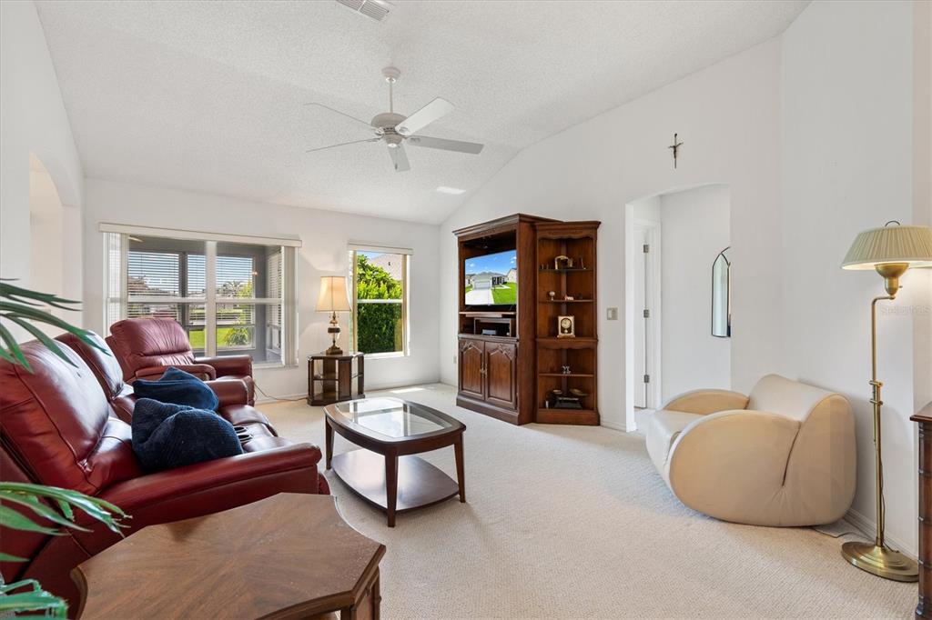 A living room features a red leather sofa, a beige armchair, and a wooden entertainment center — 811 SAN SALVADOR DRIVE, THE VILLAGES, FL