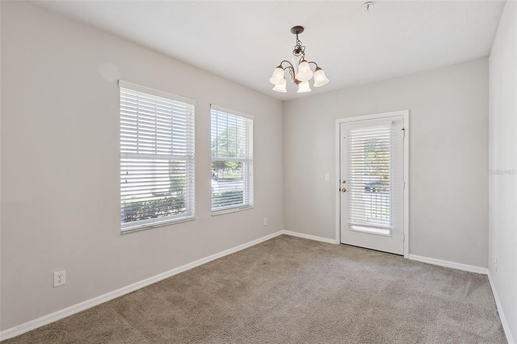 An empty room with beige carpet, light gray walls, two windows, and a glass-paneled door — 5408 CARAMELLA DRIVE, ORLANDO, FL