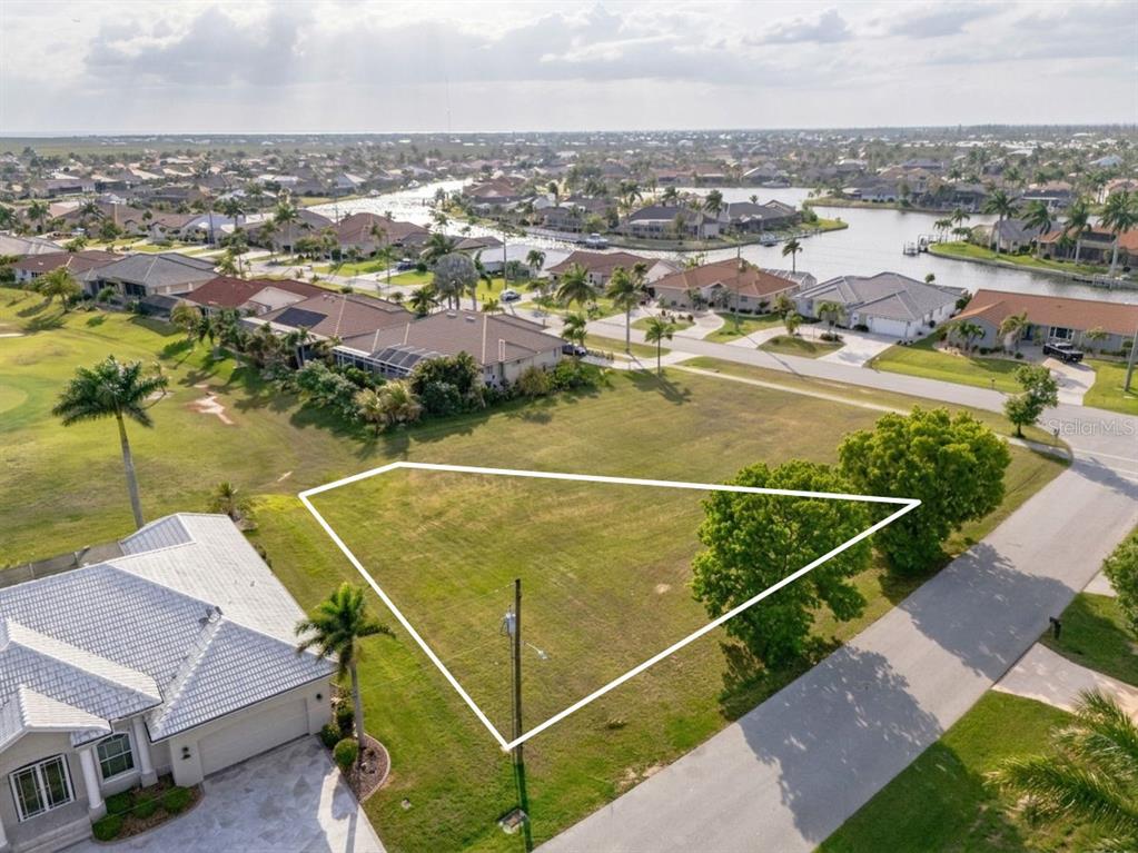 An aerial view shows a vacant, triangular-shaped residential lot bordered by a road and houses — 3707 BORDEAUX DRIVE, PUNTA GORDA, FL