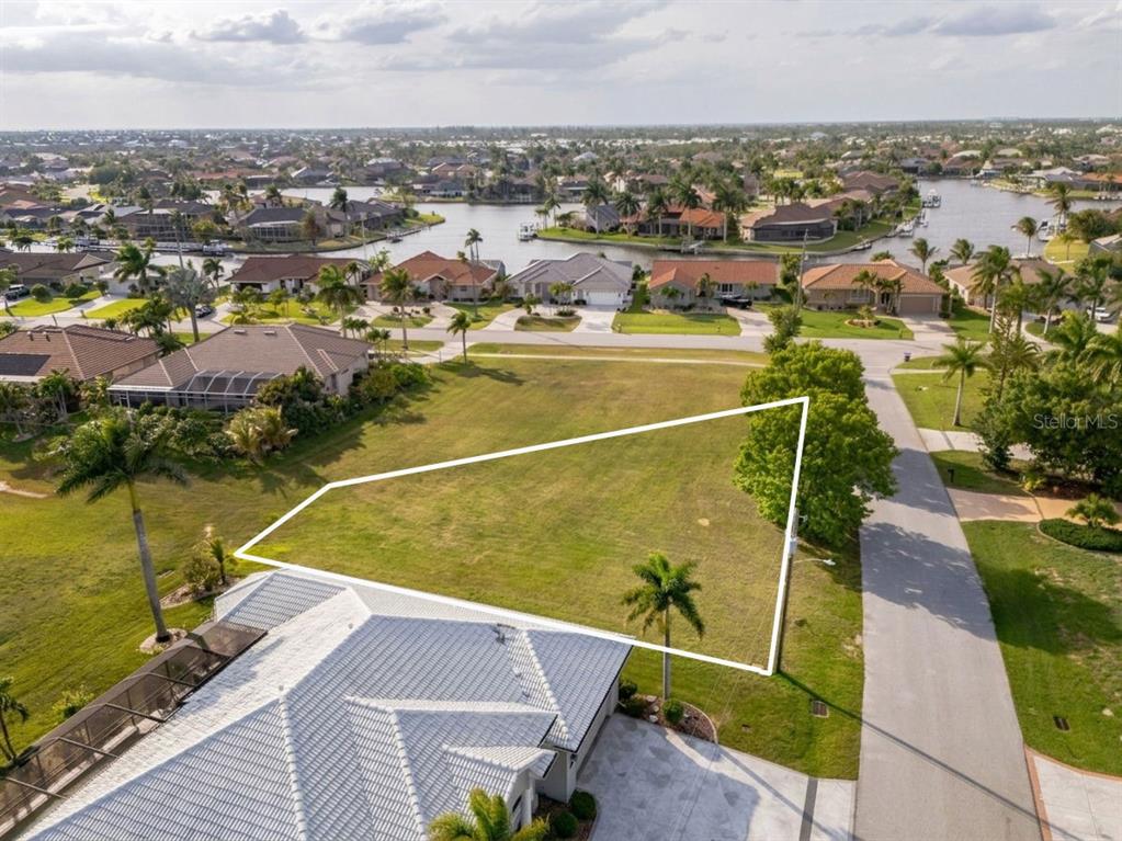 An aerial view shows a vacant, trapezoidal residential lot bordered by a road and houses — 3707 BORDEAUX DRIVE, PUNTA GORDA, FL