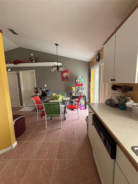 A kitchen with white cabinets and tile flooring opens into a dining area with red chairs — 4250 WORTHINGTON PLACE, MASCOTTE, FL