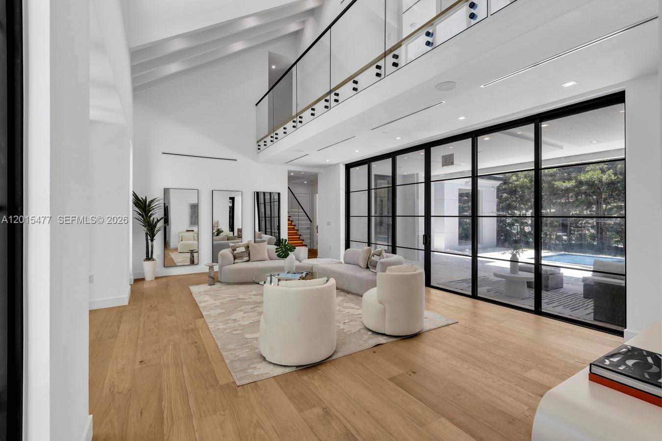 A bright living room features high vaulted ceilings, light wood floors, and large glass doors — 1220 S Alhambra Cir, Coral Gables FL 33146, CORAL GABLES, FL