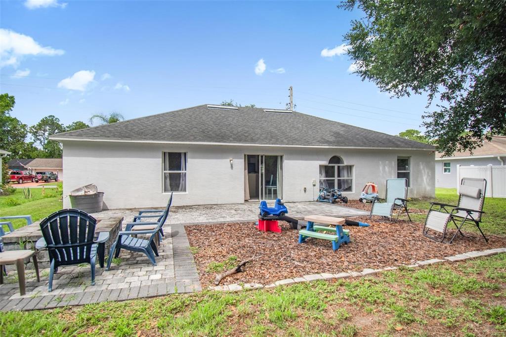 The backyard features a white stucco house, a paved patio, and a wood-mulched play area — 195 PARKVIEW DRIVE, PALM COAST, FL