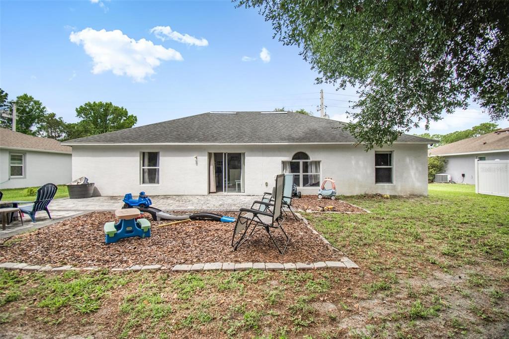 The backyard of a single-story house features a patio, a mulch play area, and lawn — 195 PARKVIEW DRIVE, PALM COAST, FL