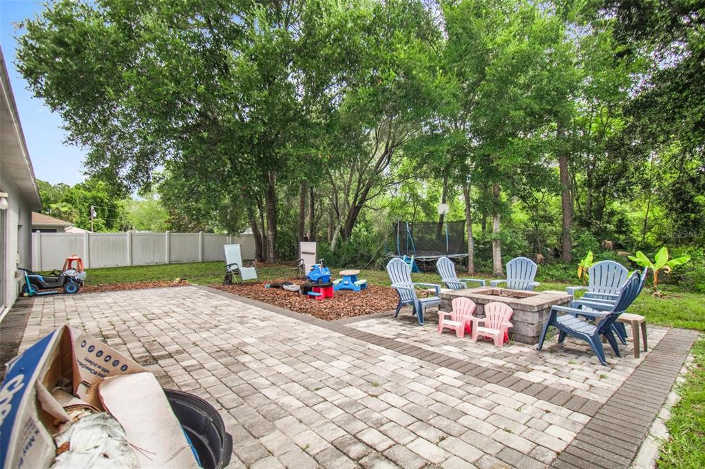 A backyard patio features a stone fire pit, blue Adirondack chairs, and a mulch play area — 195 PARKVIEW DRIVE, PALM COAST, FL