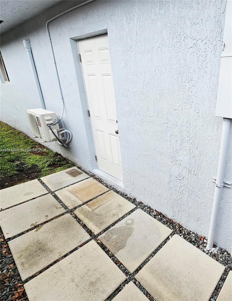 A white exterior door sits beside an air conditioning unit on a paved patio area — 20100 NW 37, Miami Gardens FL 33055, MIAMI GARDENS, FL