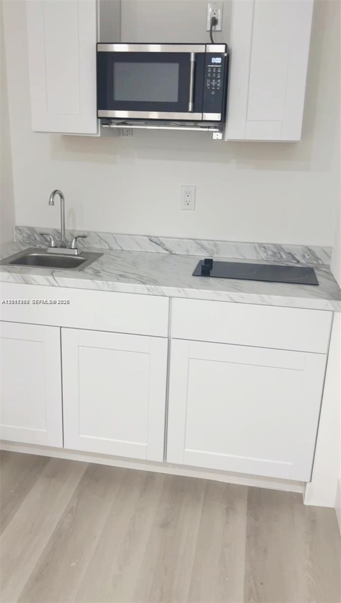 A small kitchen area features white cabinets, a marble-patterned countertop, a sink, and a microwave — 20100 NW 37, Miami Gardens FL 33055, MIAMI GARDENS, FL
