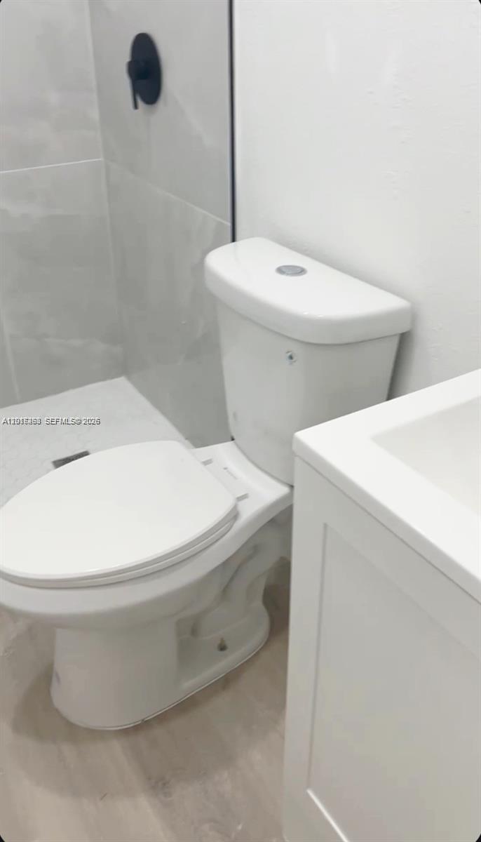 A white toilet is positioned next to a bathroom vanity and a tiled shower area — 20100 NW 37, Miami Gardens FL 33055, MIAMI GARDENS, FL