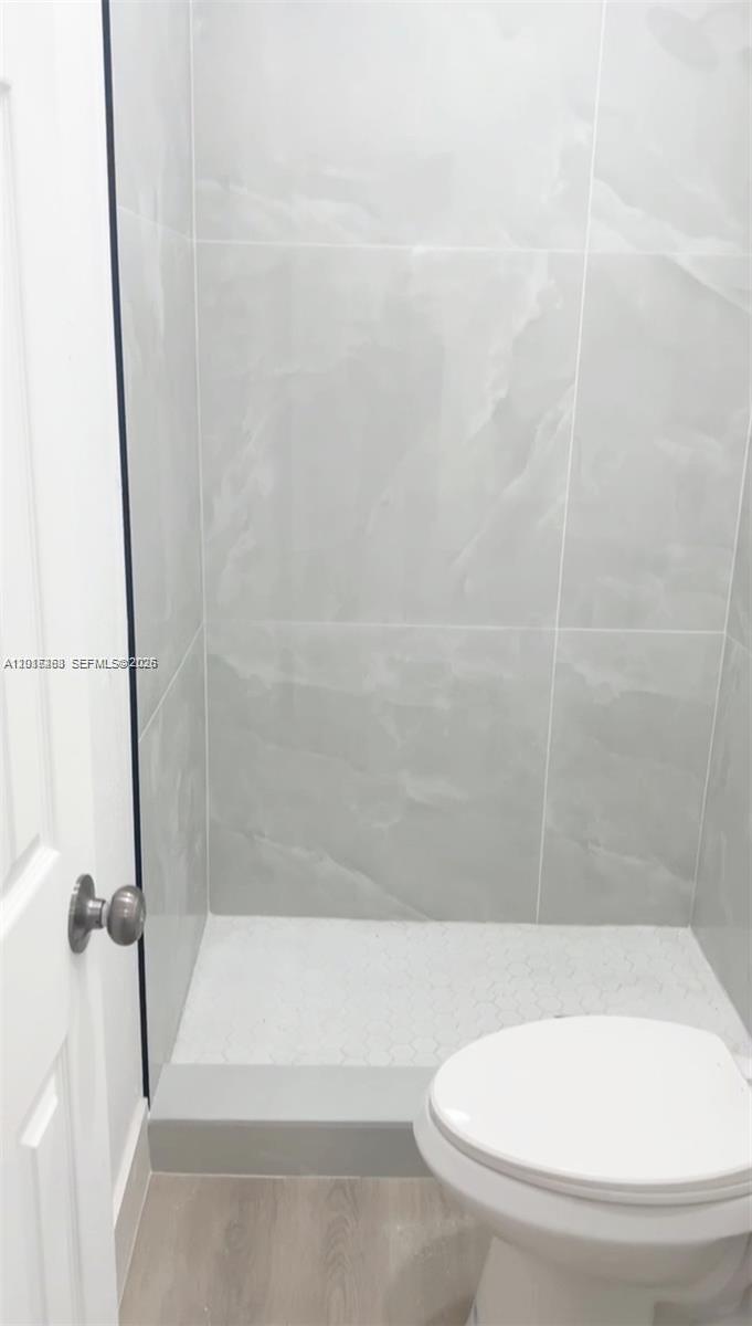 A bathroom features a walk-in shower with light gray marble-look tiles and a white toilet — 20100 NW 37, Miami Gardens FL 33055, MIAMI GARDENS, FL