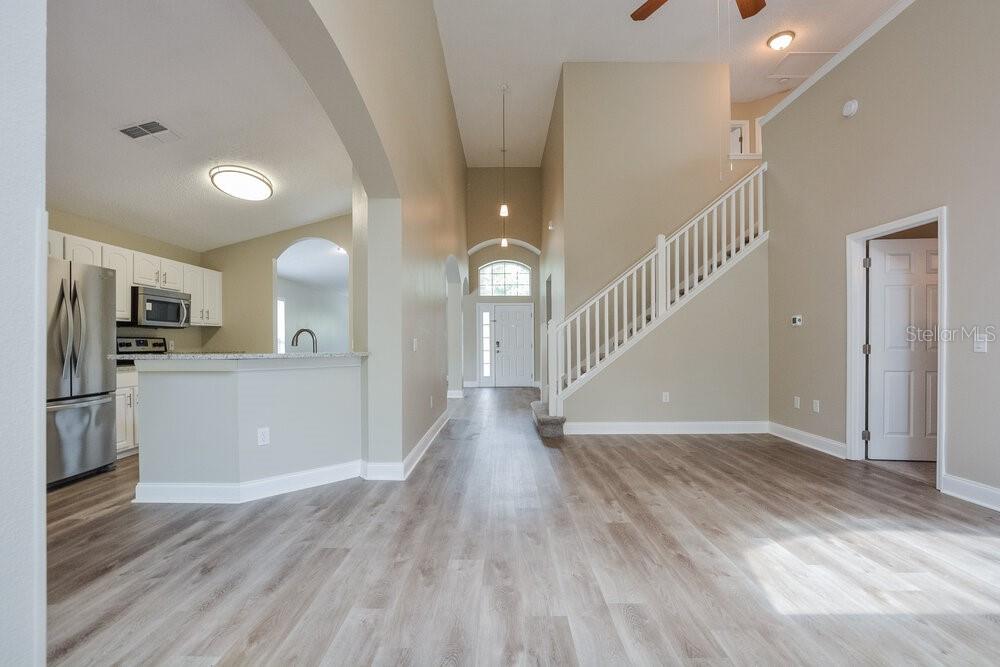 A view of an open-concept living area with light wood-look flooring and a staircase — 8344 LAKE AMHURST TRAIL, ORLANDO, FL