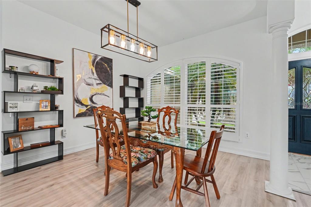 A dining room features a glass-top table, wooden chairs, open shelving, and a modern light fixture — 12507 ROYAL DUBLIN AVENUE, ODESSA, FL