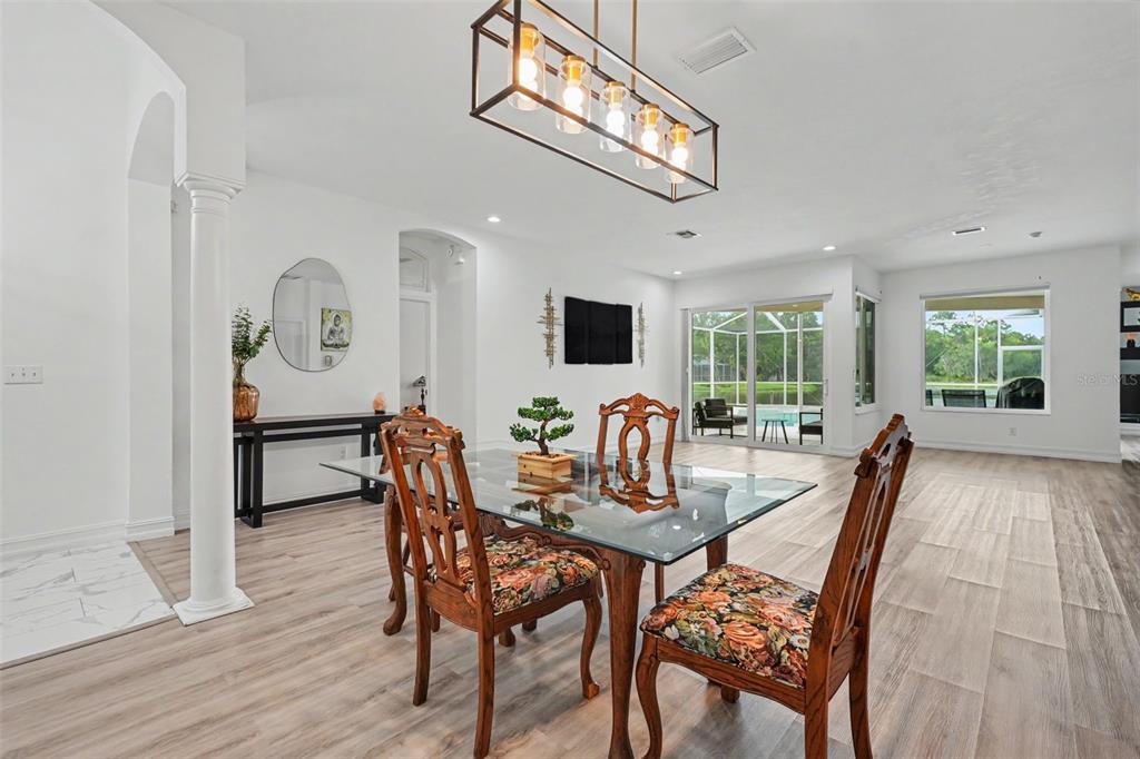 A dining room features a glass-top table, wooden chairs, and a rectangular pendant light fixture — 12507 ROYAL DUBLIN AVENUE, ODESSA, FL