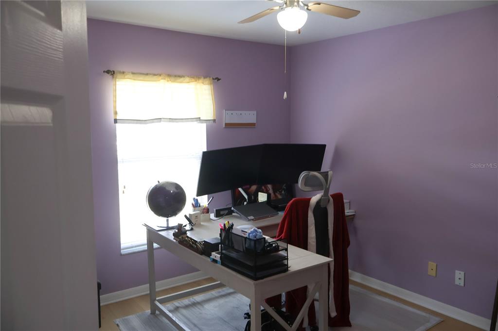 A home office with purple walls, a desk with dual monitors, and a ceiling fan — 5396 CARAMELLA DRIVE, ORLANDO, FL