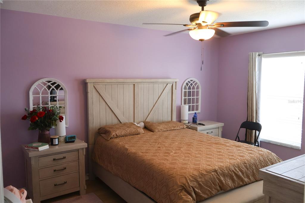 A bedroom features lavender walls, a light wood bed frame, and a ceiling fan — 5396 CARAMELLA DRIVE, ORLANDO, FL